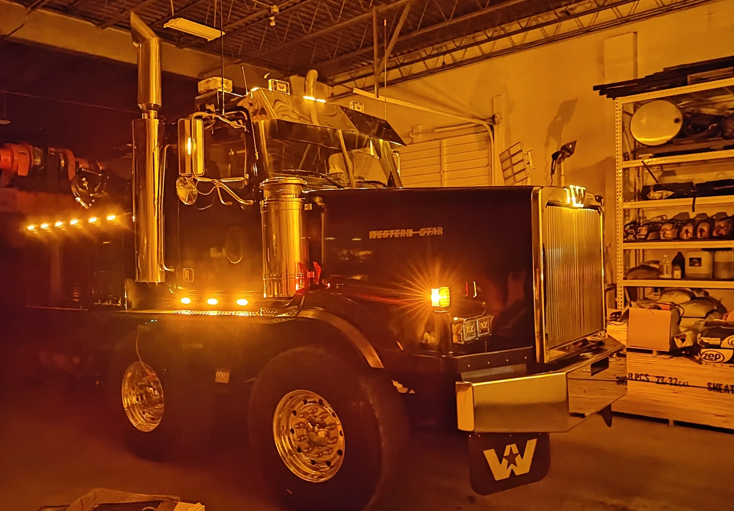 Close-up of Western Star truck inside Zielke Towing’s garage during nighttime electrical system checkup under amber lights