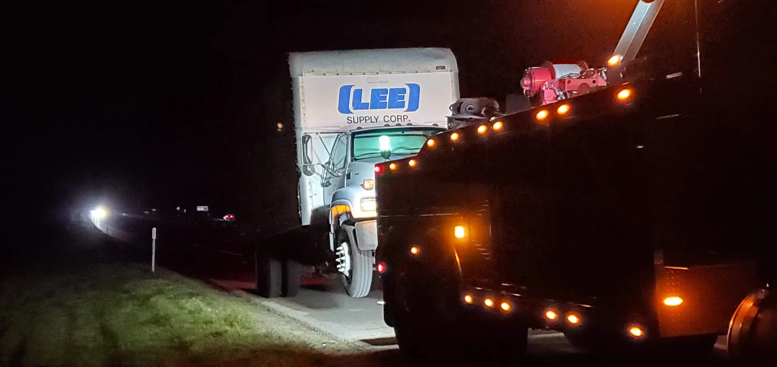 Zielke Towing performs nighttime box truck recovery from the side of the highway under bright lights
