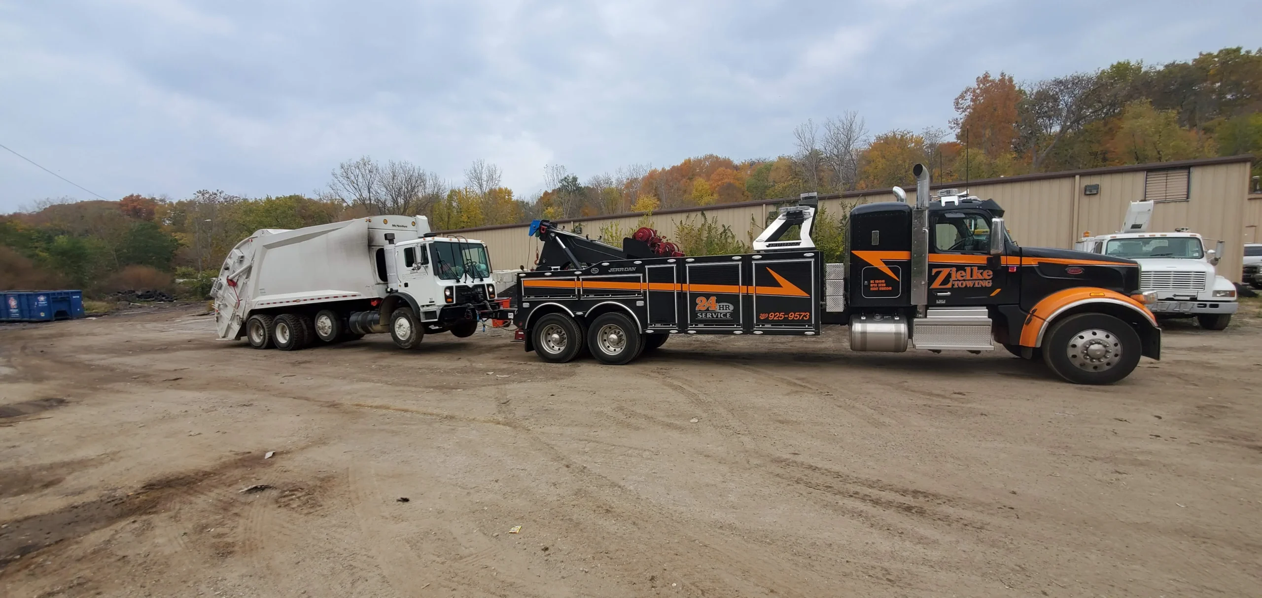 Zielke Towing performing heavy duty towing for a broken-down garbage truck in a dirt industrial yard