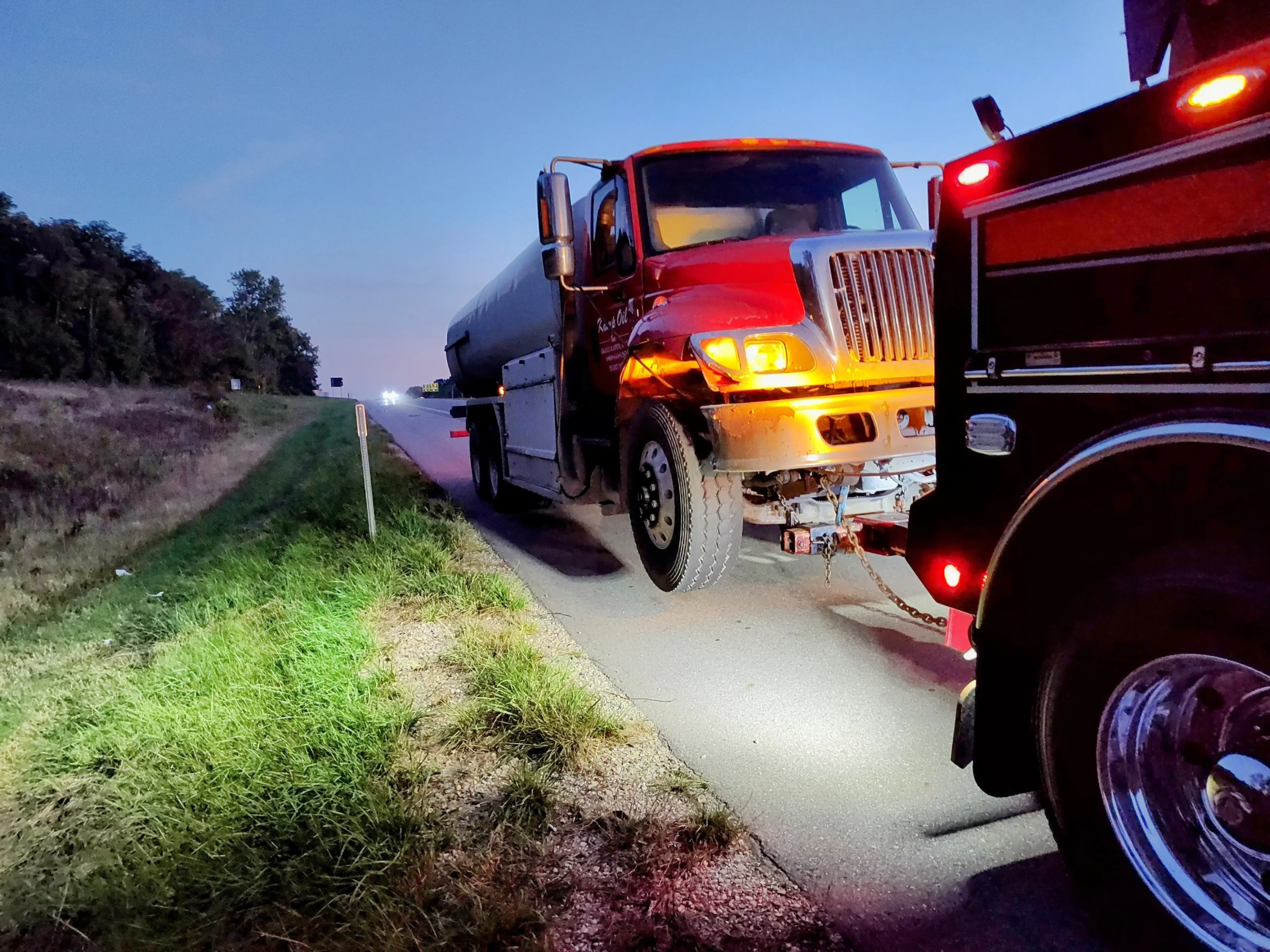Heavy duty towing service handling tanker truck breakdown near highway shoulder