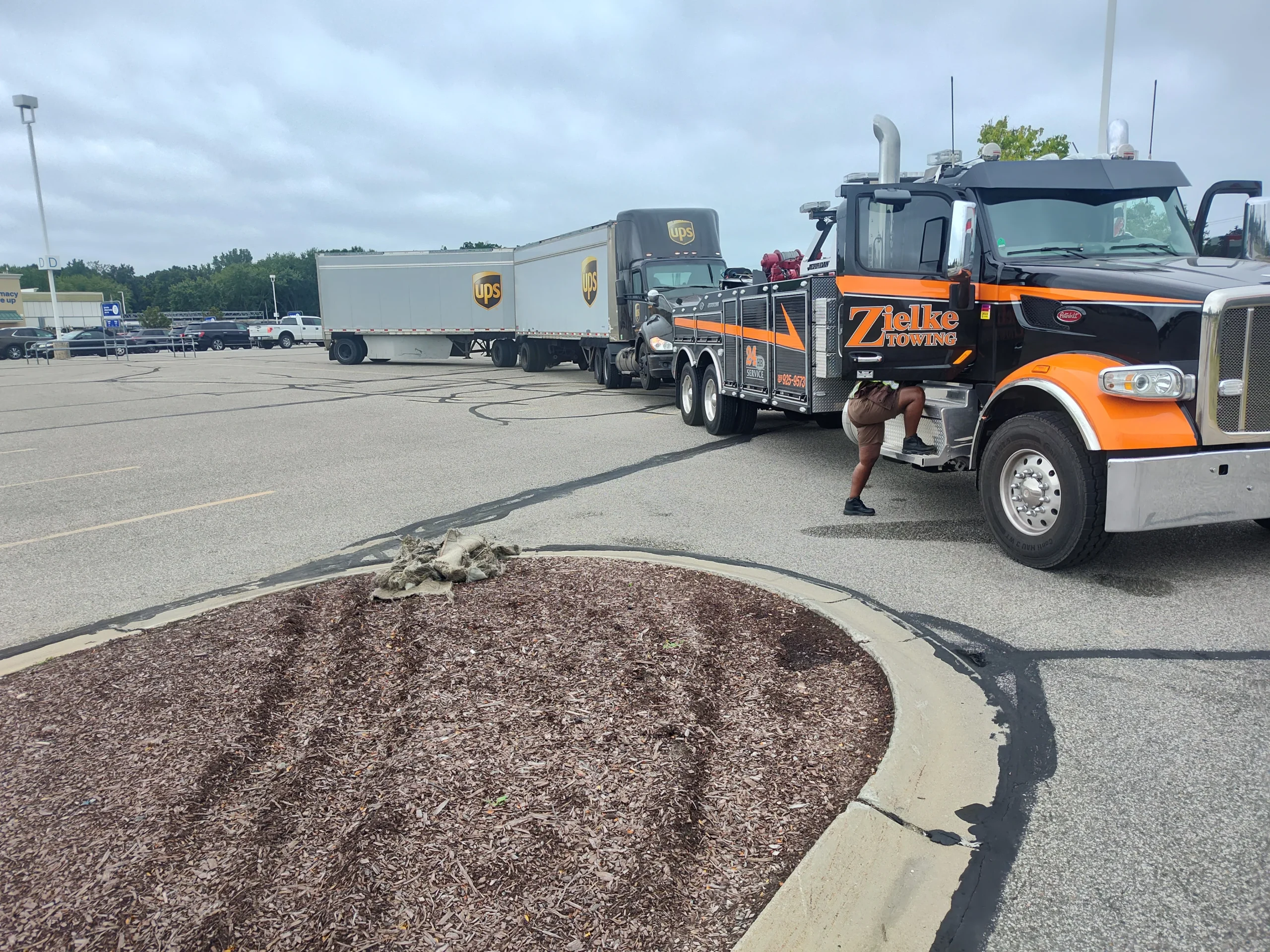 Zielke Towing heavy duty wrecker connected to a UPS semi truck in parking lot for roadside assistance