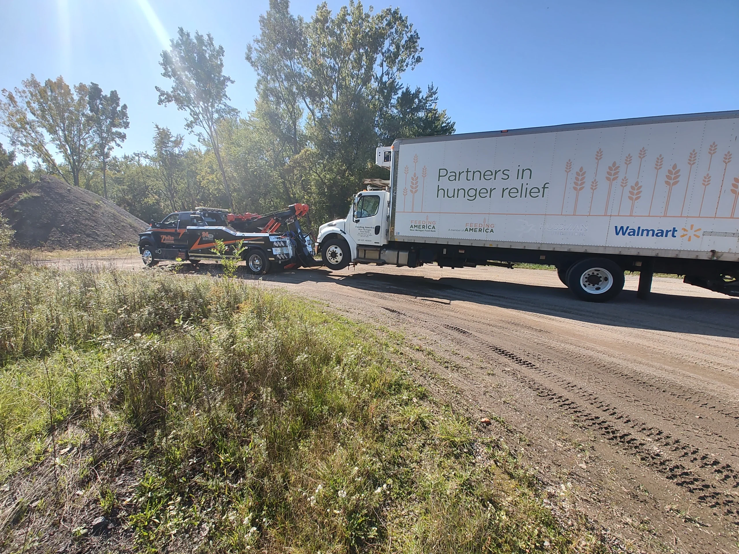 Zielke heavy duty tow truck assisting disabled Walmart Partners in Hunger Relief box truck