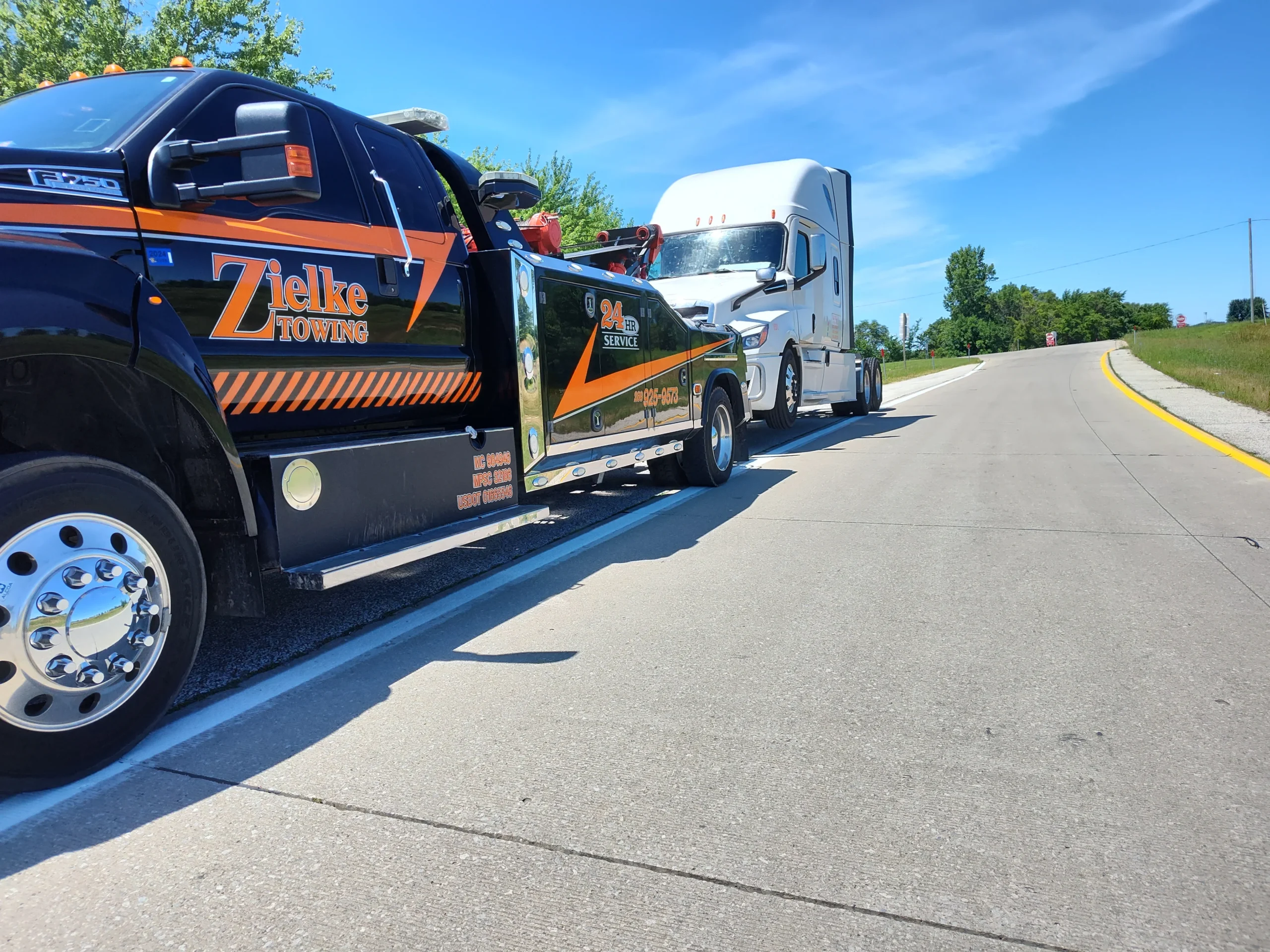 Zielke tow truck pulling white semi up on-ramp during long haul tow in Benton Harbor
