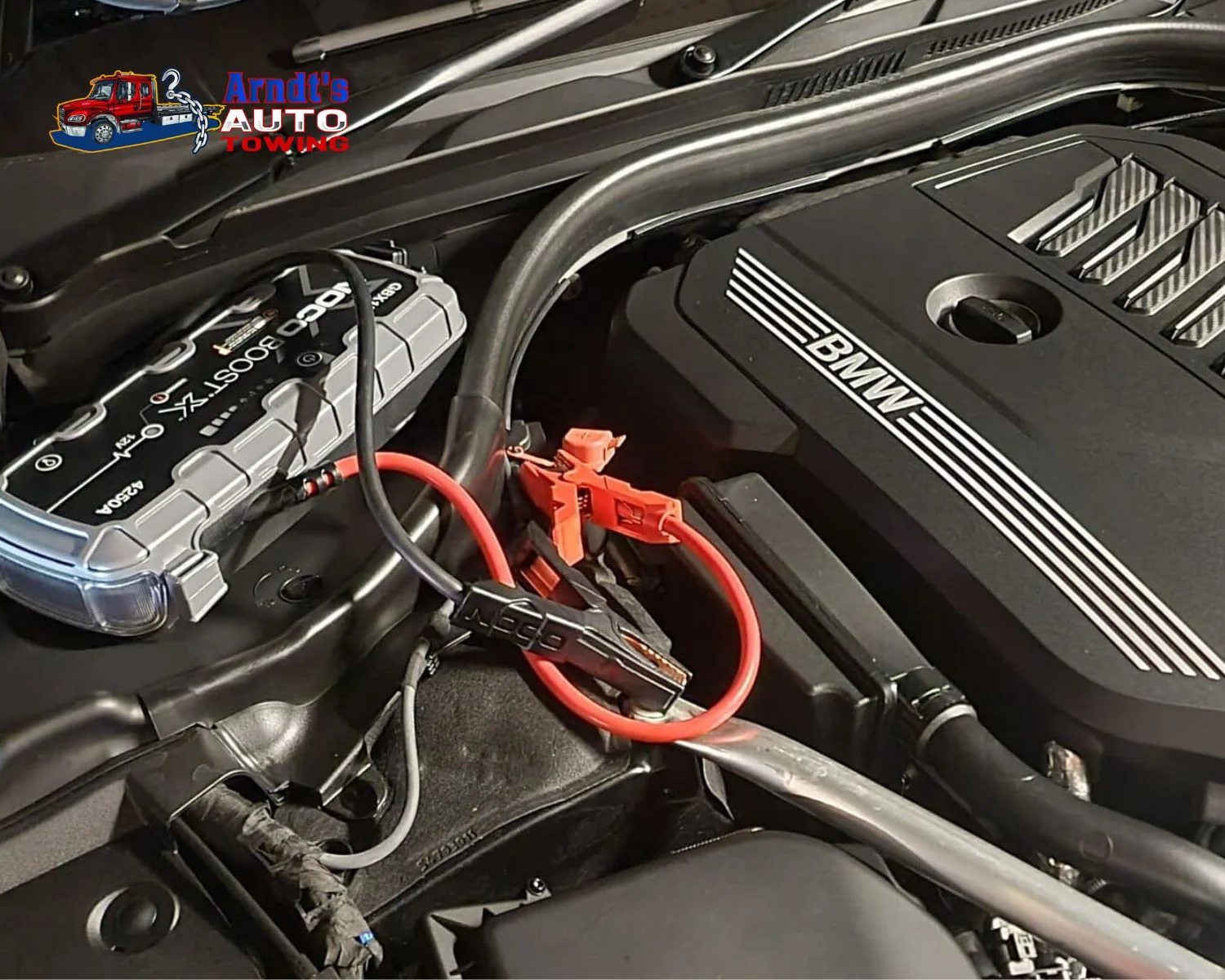 Boost jump starter connected to BMW engine by Arndt’s Auto Towing