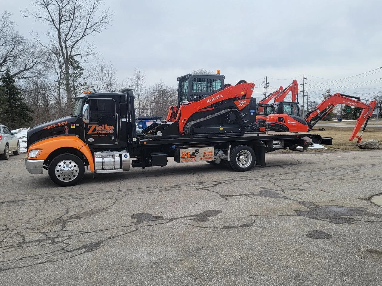 Zielke Towing light duty flatbed transporting a Kubota skid steer loader in a construction equipment lot