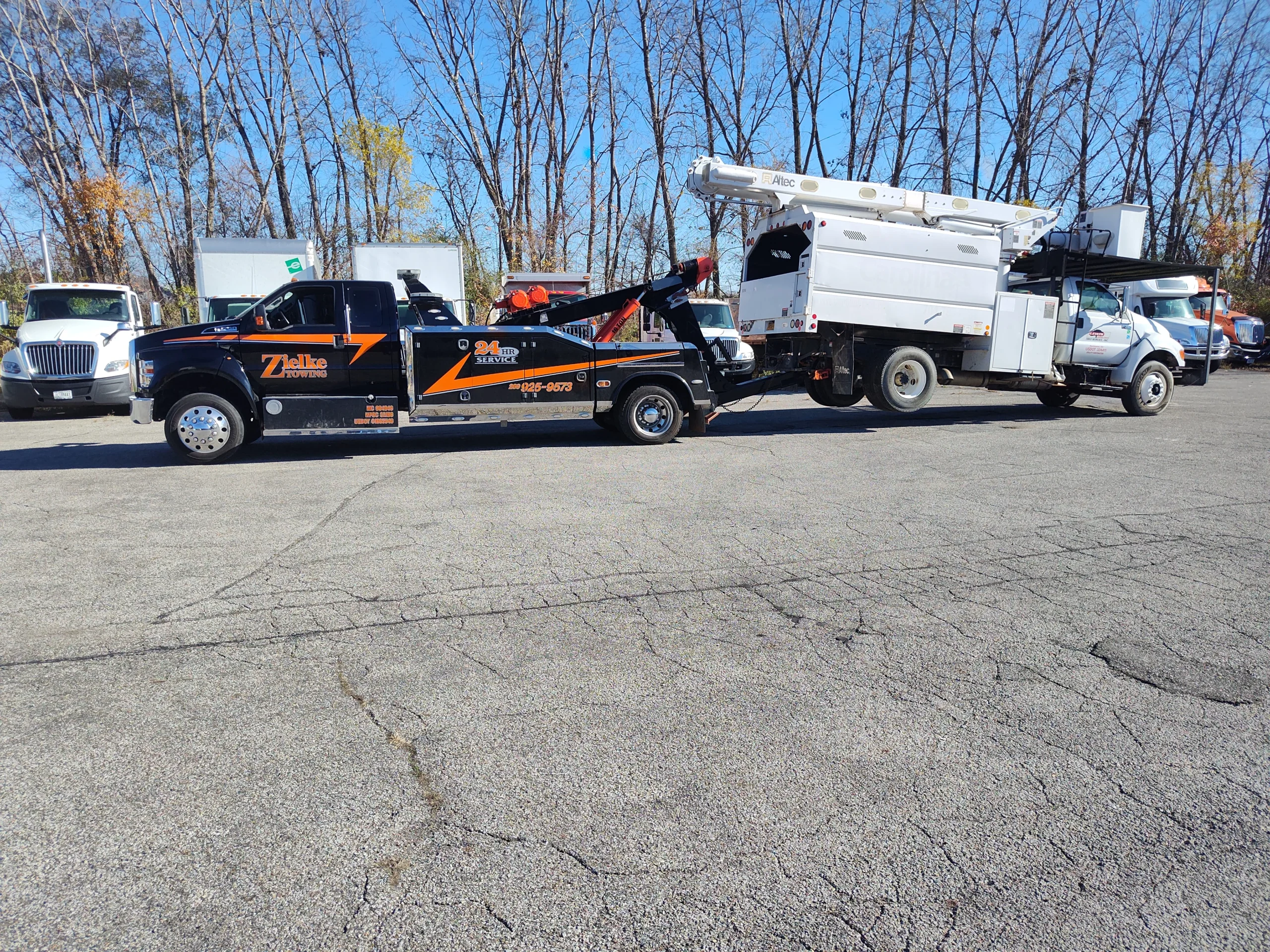 Zielke Towing performing medium duty towing of a white utility bucket truck in a paved lot