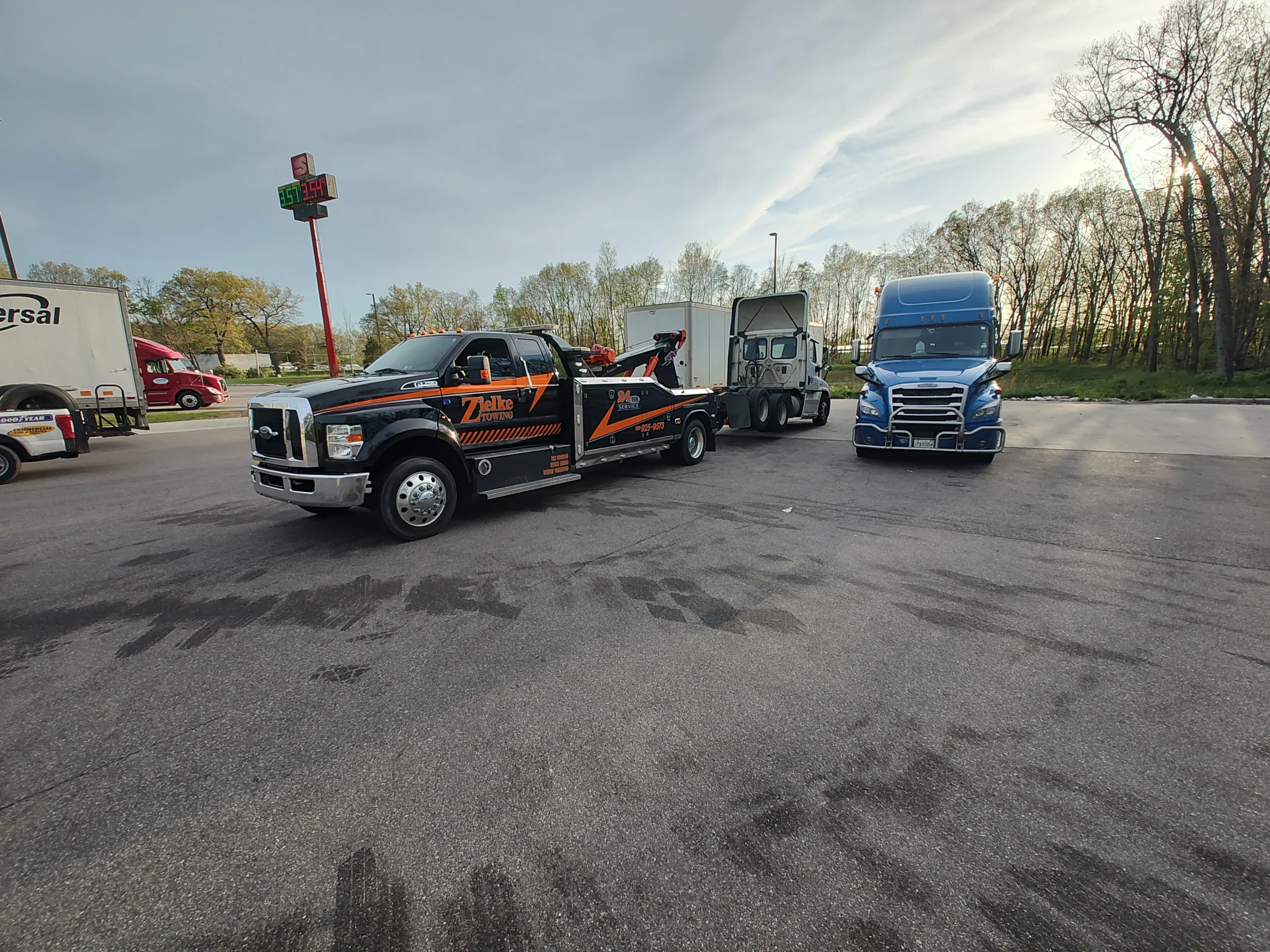 Medium duty tow truck from Zielke Towing parked at a fuel stop next to multiple semi trucks