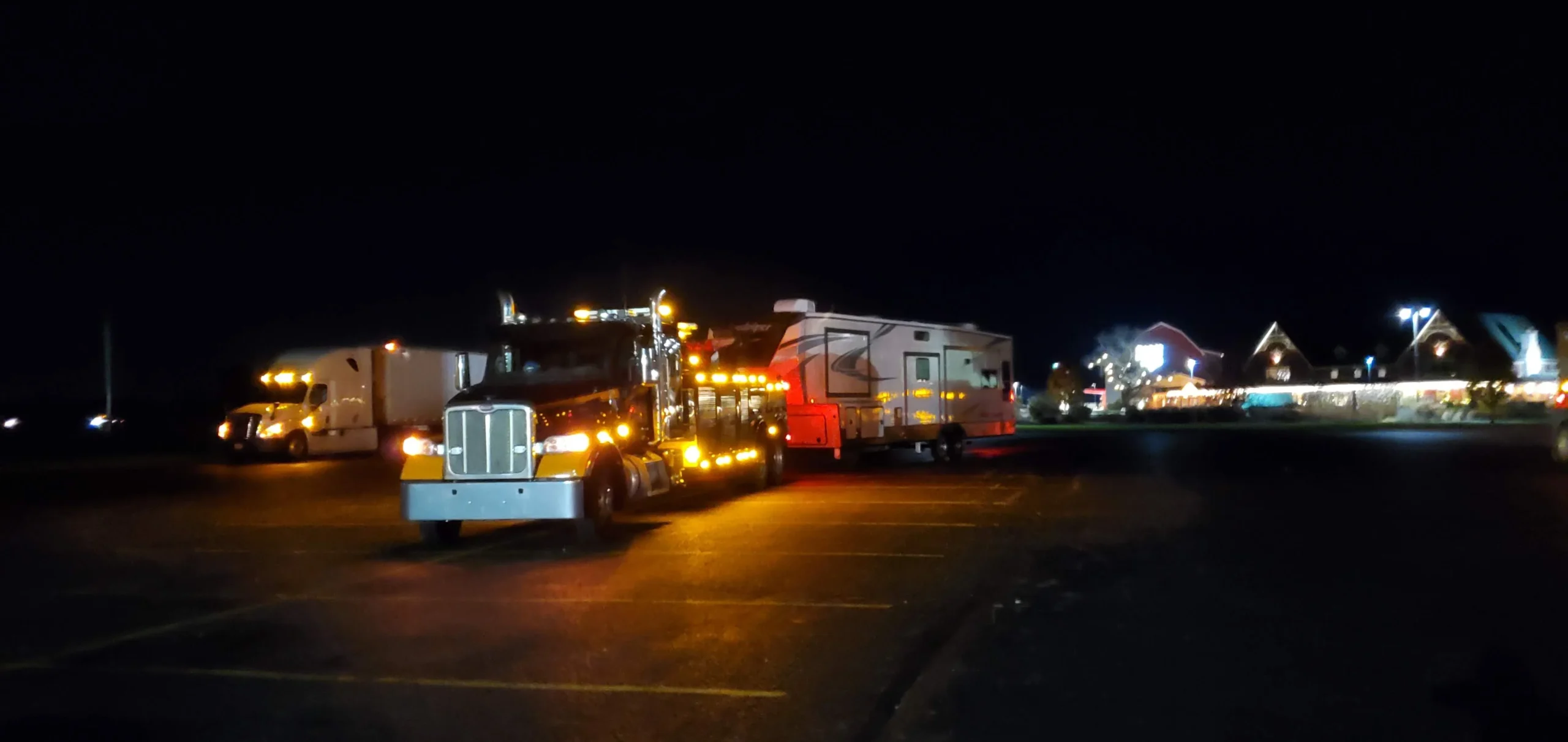 Zielke heavy-duty wrecker towing an RV from a parking lot at night with lights on