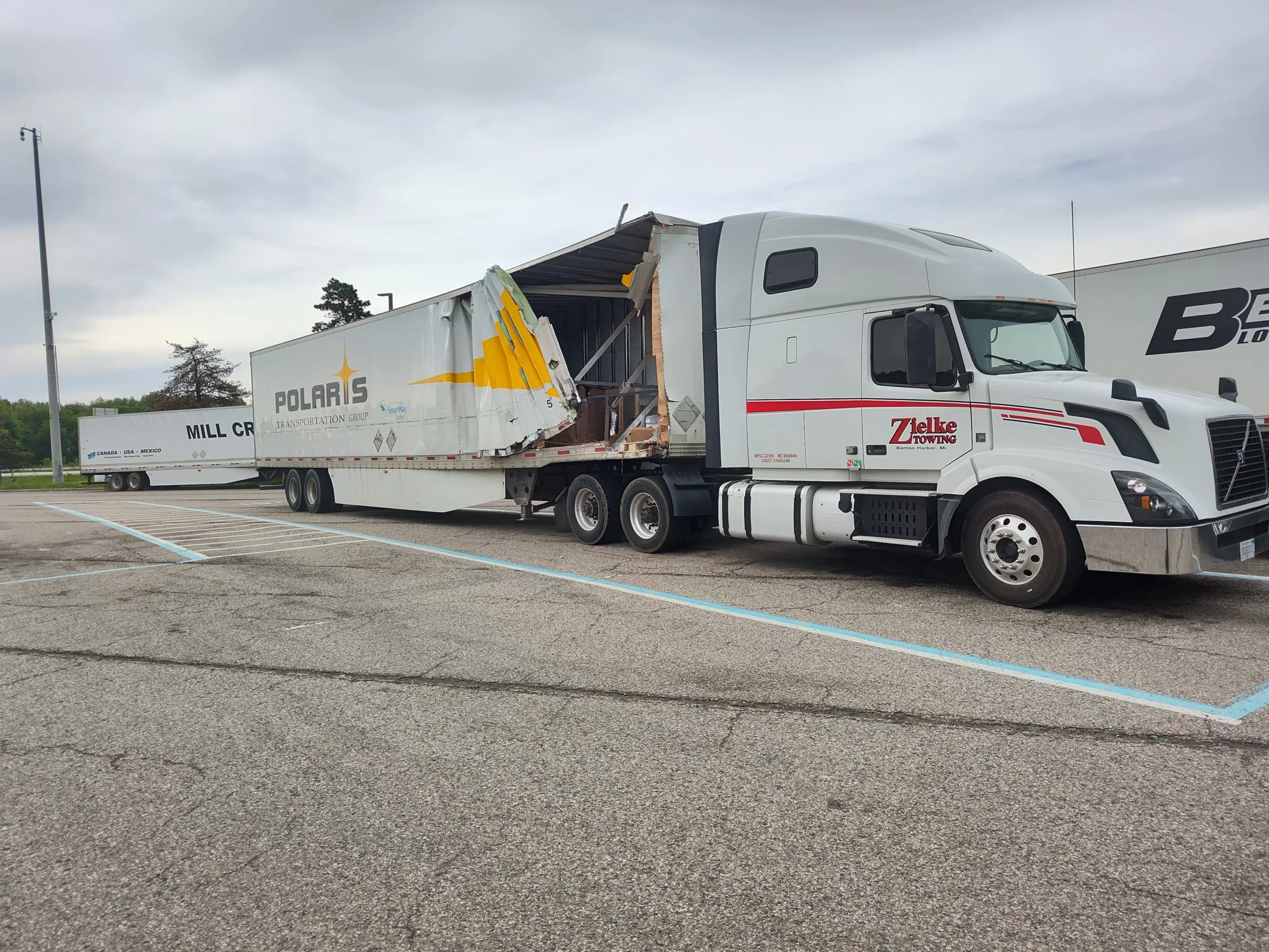 Zielke Towing semi-truck recovering a damaged Polaris trailer in a truck stop parking lot