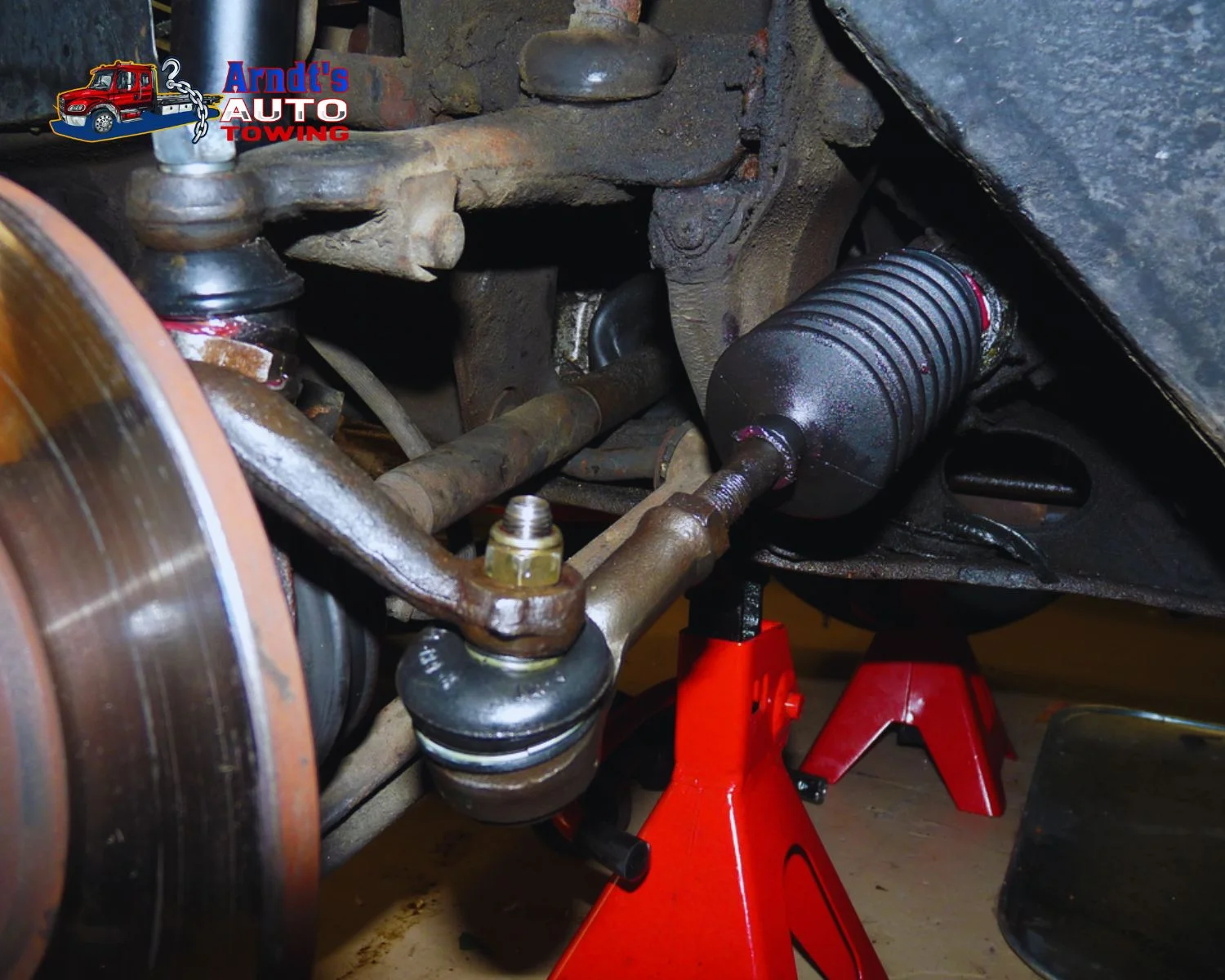 Detailed image of steering boot, tie rod, and jack stands during steering and suspension service