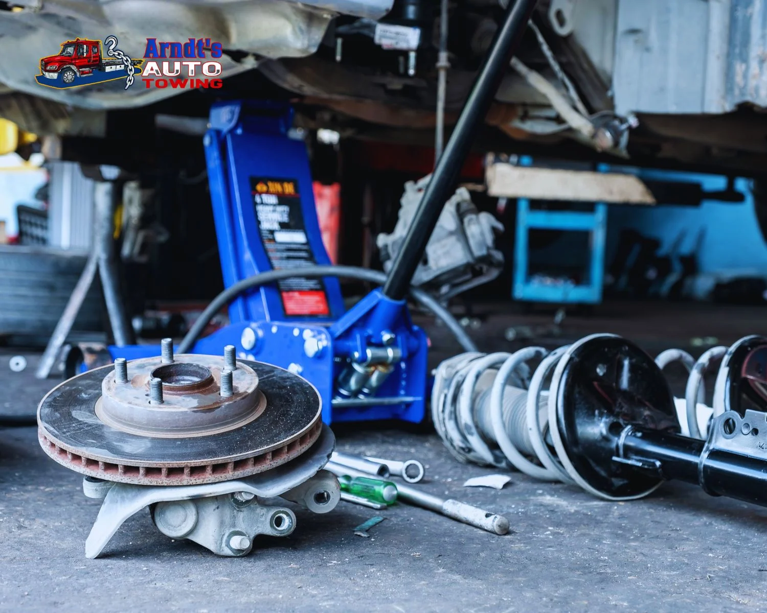 Suspension strut and disc brake rotor being replaced in Arndt's Auto Towing garage