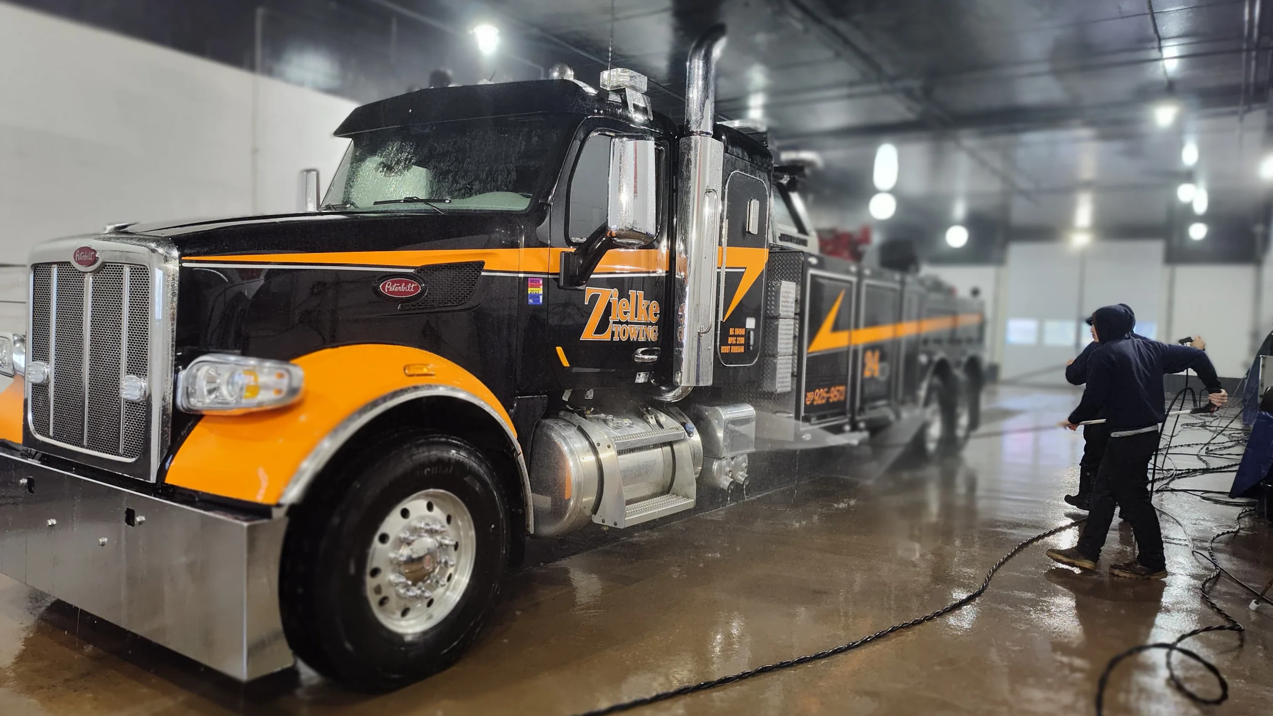Zielke Towing heavy-duty Peterbilt truck undergoing drivetrain cleaning inside indoor service wash bay