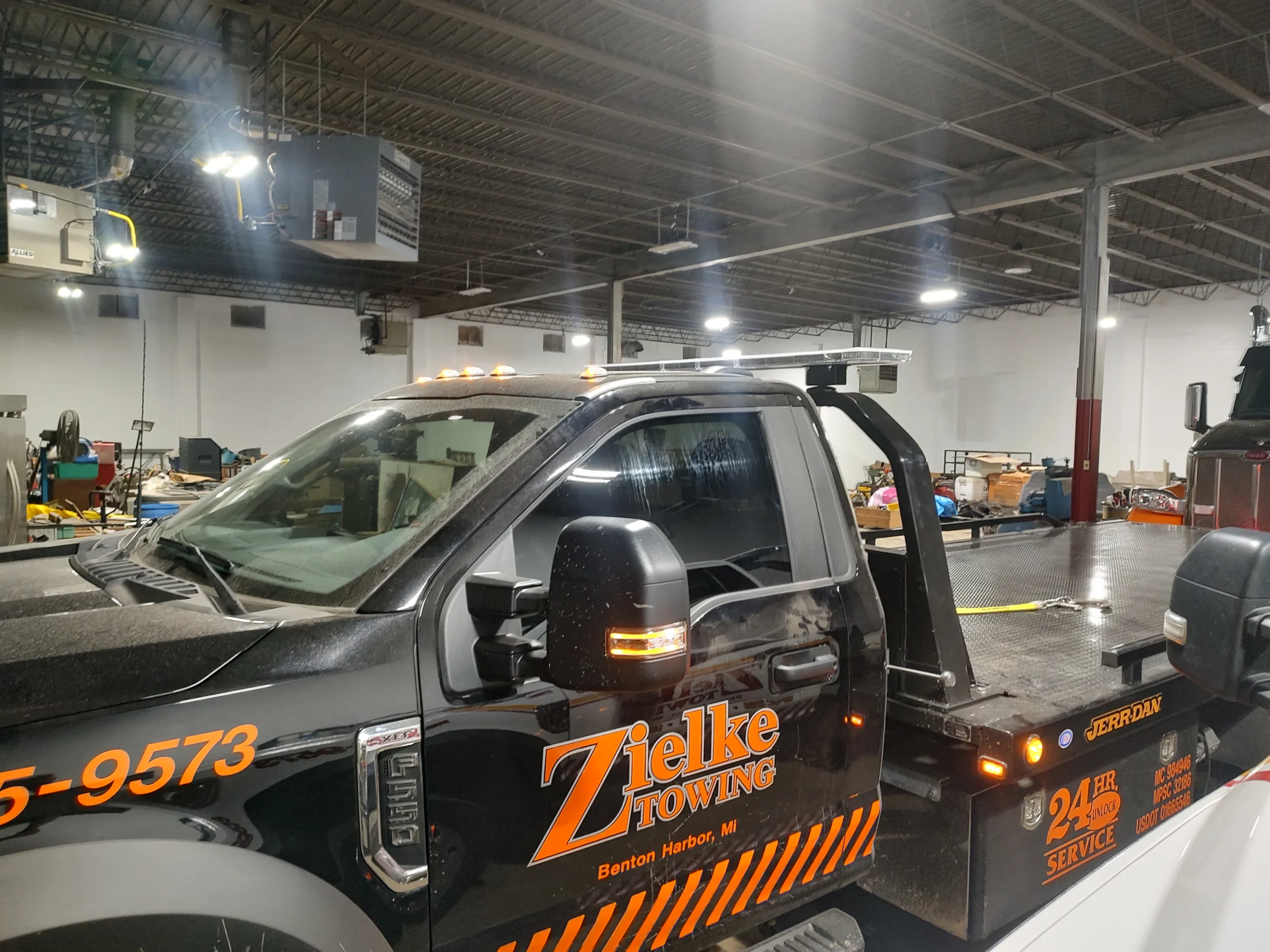 Close-up side view of Zielke Towing flatbed tow truck showing fuel service tools and gear in workshop
