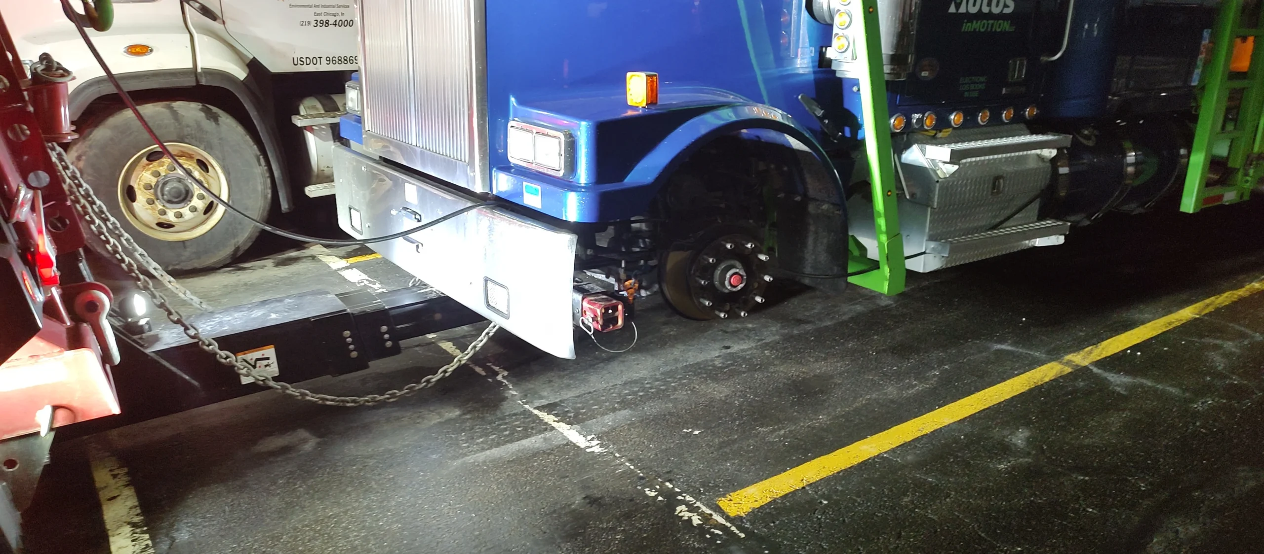 Zielke Towing technician performs wheel lift towing hookup on disabled semi truck at night
